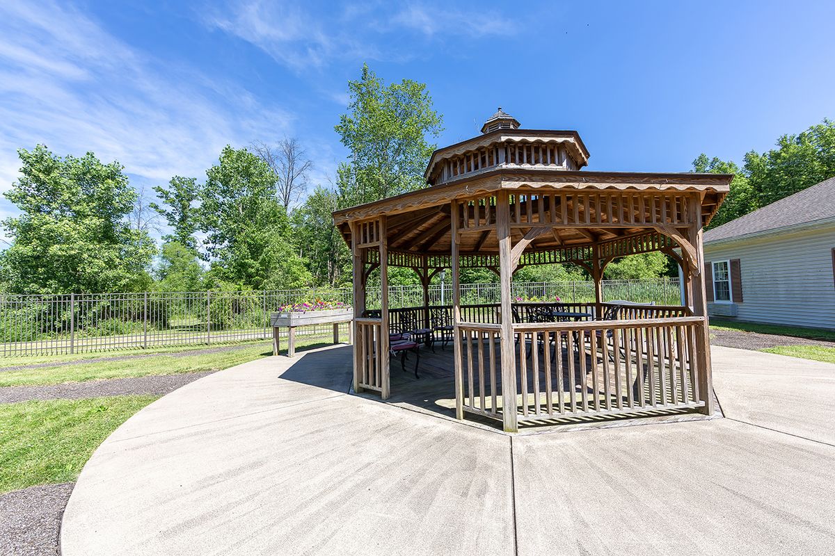 A wooden gazebo in a scenic park setting under a clear blue sky.