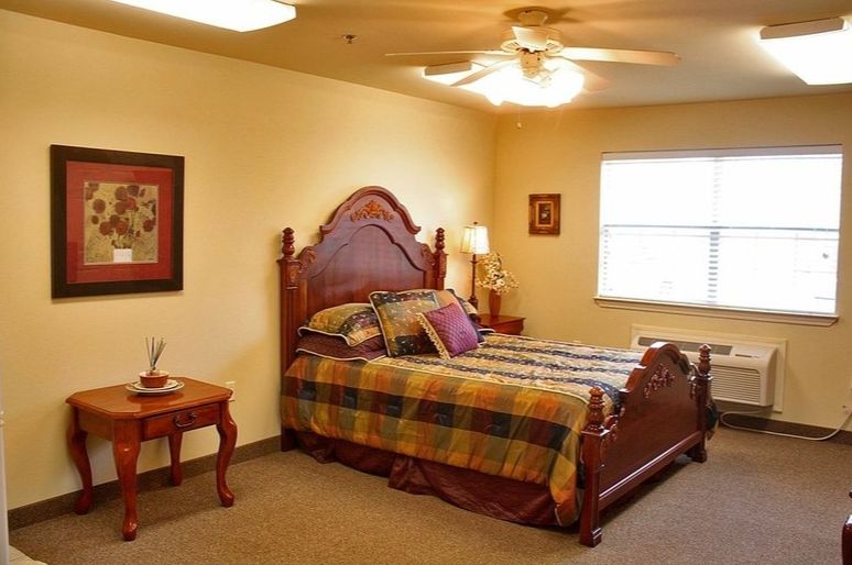 A cozy bedroom with a wooden bed frame and plaid bedding, featuring warm lighting.