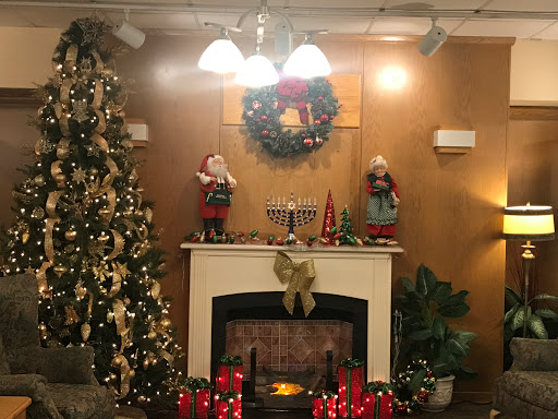 A cozy Christmas corner with decorations, a glowing fireplace, and festive elements.