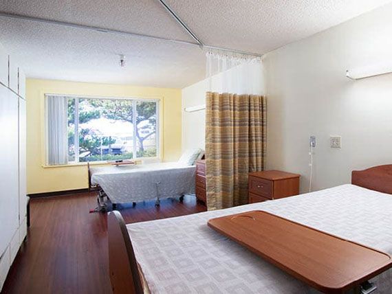 A hospital room with two patient beds and a privacy curtain.