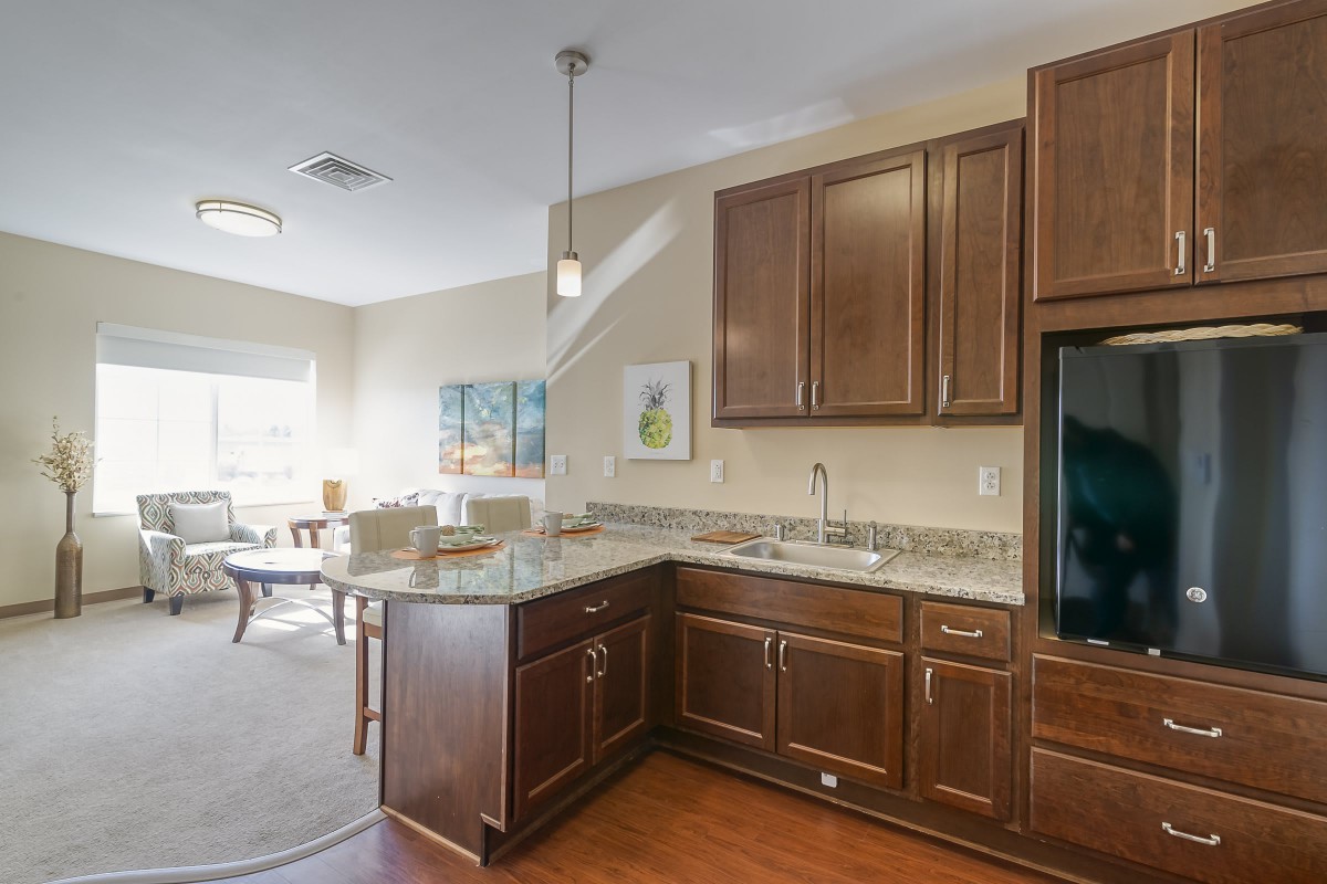 A modern kitchen with dark wood cabinets, granite countertops, and an open concept dining area.