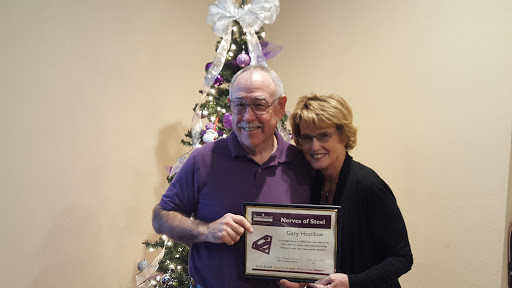 A proud moment as two individuals celebrate an achievement in front of a decorated holiday tree.