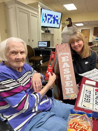 A joyful moment shared between a resident and a volunteer as they create festive Easter decorations together.