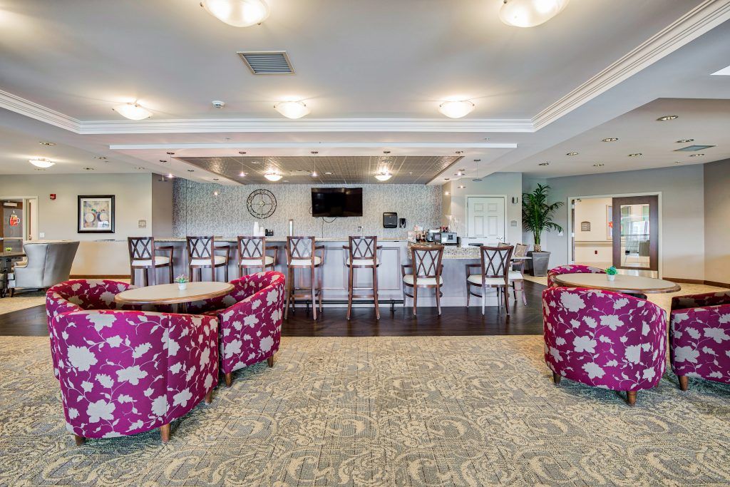 A modern bar area with vibrant seating and ample lighting, featuring floral-patterned chairs and a sleek design.