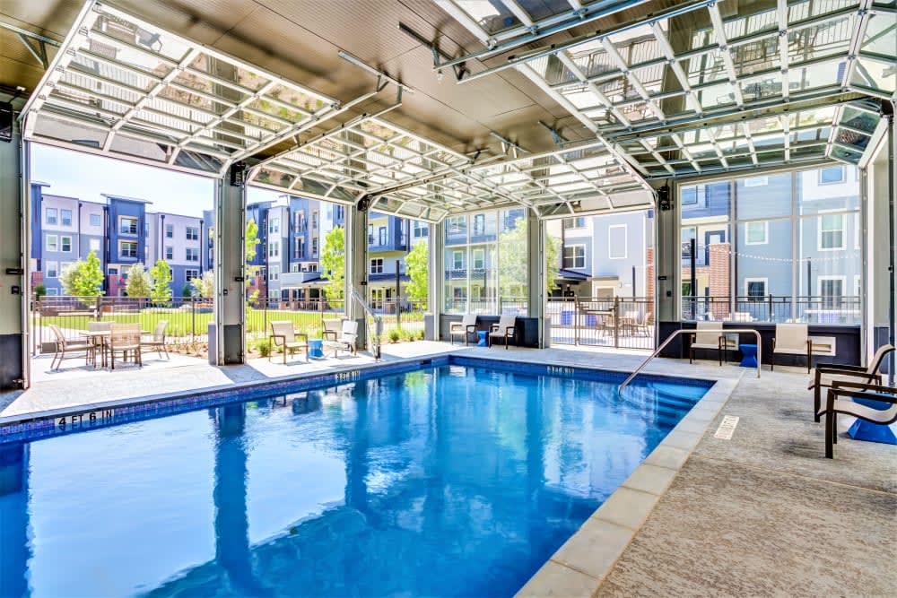 A modern indoor pool with glass walls offering a view of a residential complex.