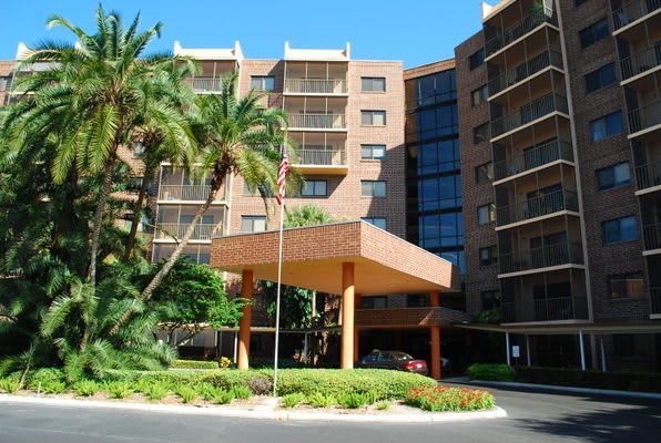 A mid-rise building with a welcoming entrance surrounded by palm trees and lush landscaping.