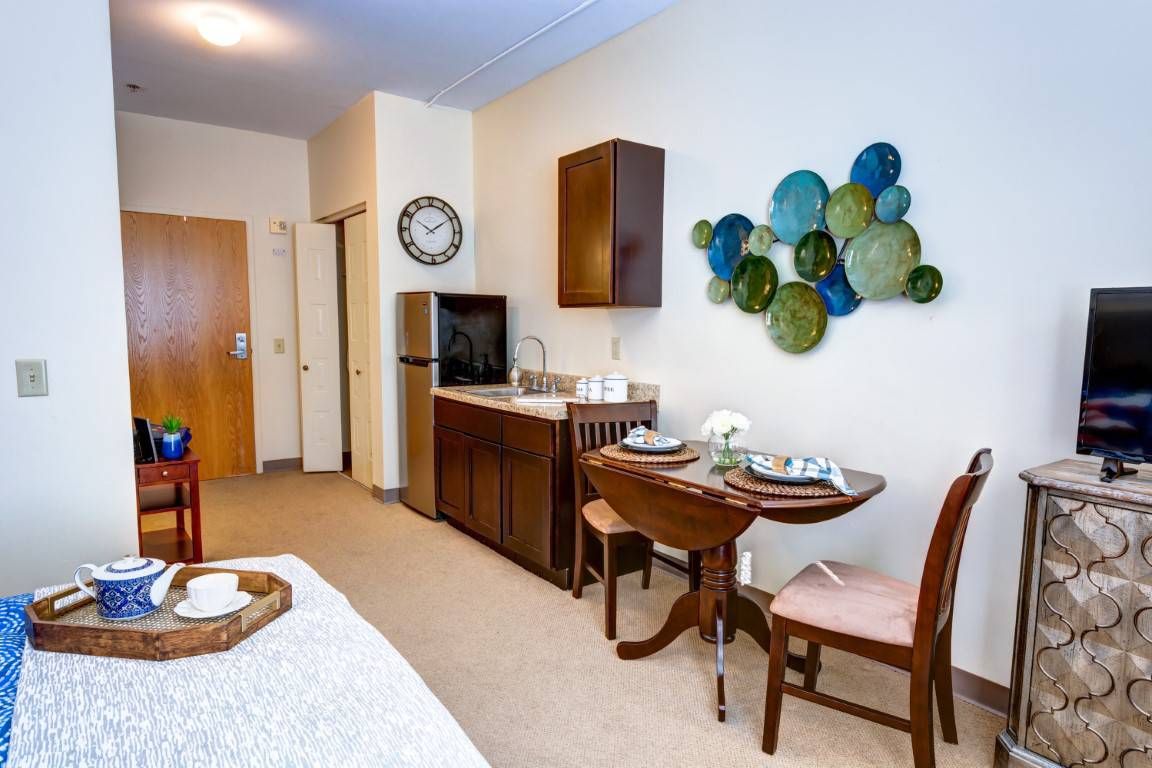 A cozy apartment interior featuring a kitchenette and a small dining area with wall art.