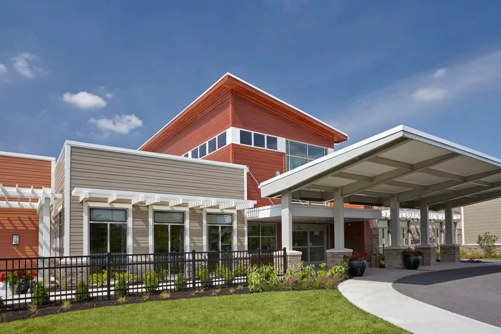 A modern building with large windows and a covered entrance, set against a clear blue sky.