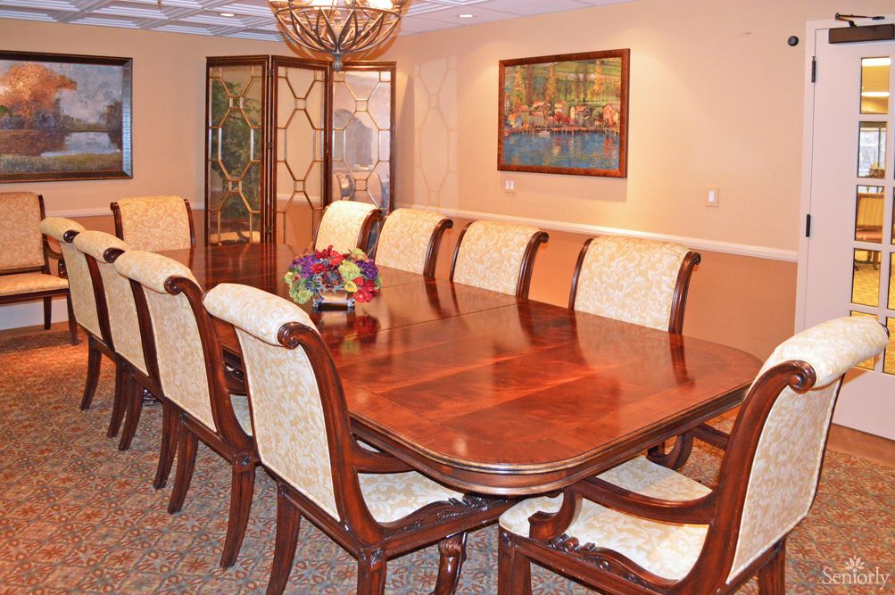 A well-furnished dining room featuring a large wooden table surrounded by upholstered chairs.