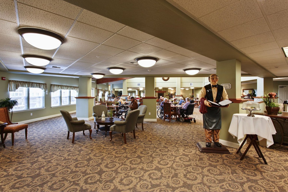 A spacious restaurant interior with a dining area featuring multiple tables and chairs, decorated with a waiter statue.