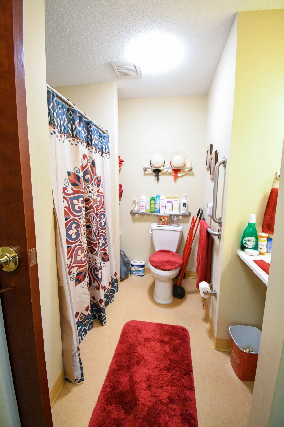 A well-decorated bathroom featuring a vivid shower curtain, neatly organized toiletries, and vibrant red towels.