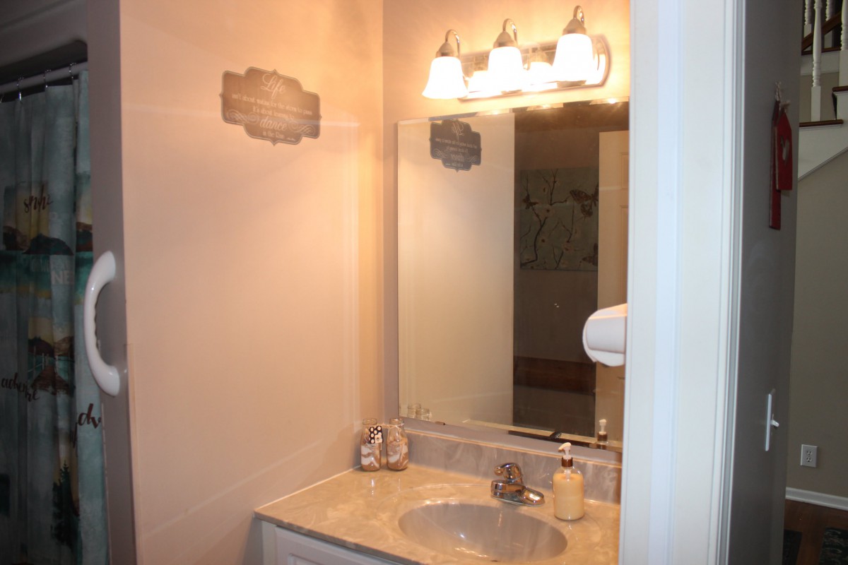 A bathroom vanity area with a sink, mirror, and overhead lighting.