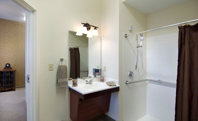 A modern bathroom with a sink, mirror, and shower area.