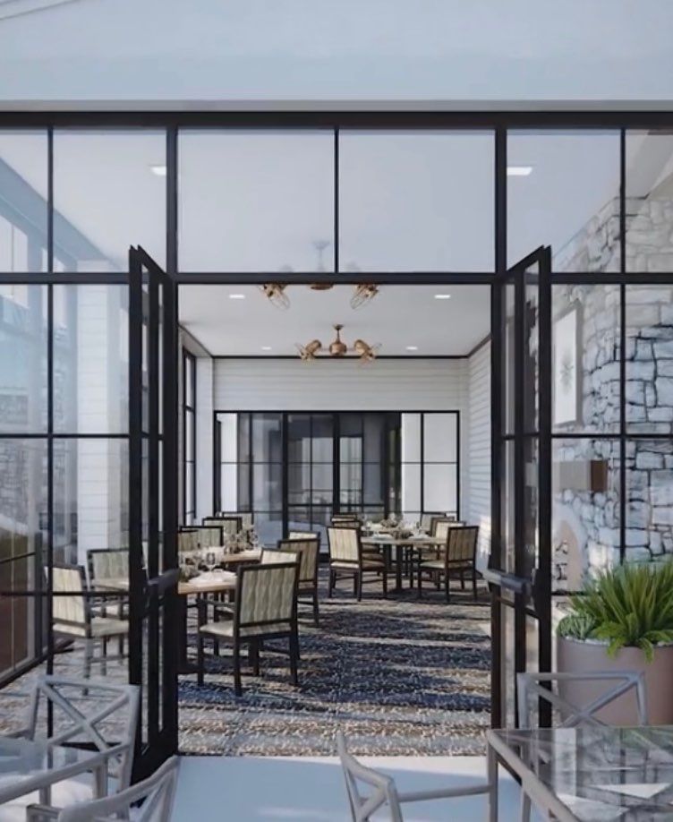 A modern restaurant interior featuring glass walls, ample natural light, and neatly arranged tables and chairs.
