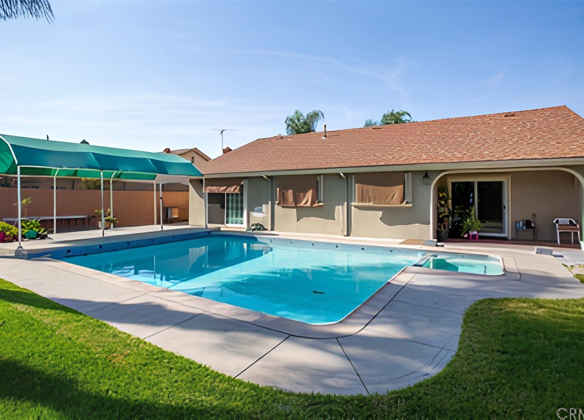 A residential backyard featuring a swimming pool and patio area.
