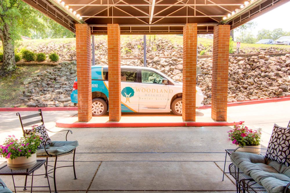 A small car parked under a covered area with brick columns.