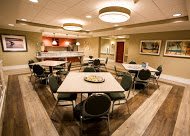 A modern dining area with neatly arranged tables and chairs under soft lighting.