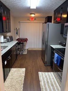 A modern kitchen featuring stainless steel appliances and wooden flooring.
