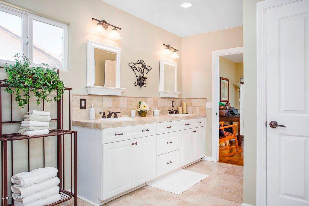 A well-lit bathroom features a double-sink vanity with neutral tones and decorative accents.