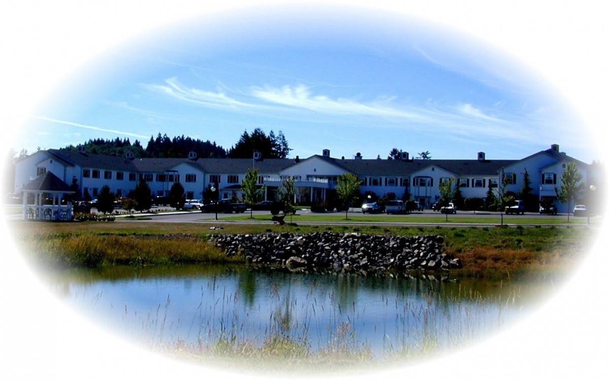 A scenic view of a building with a pond in the foreground, surrounded by nature.