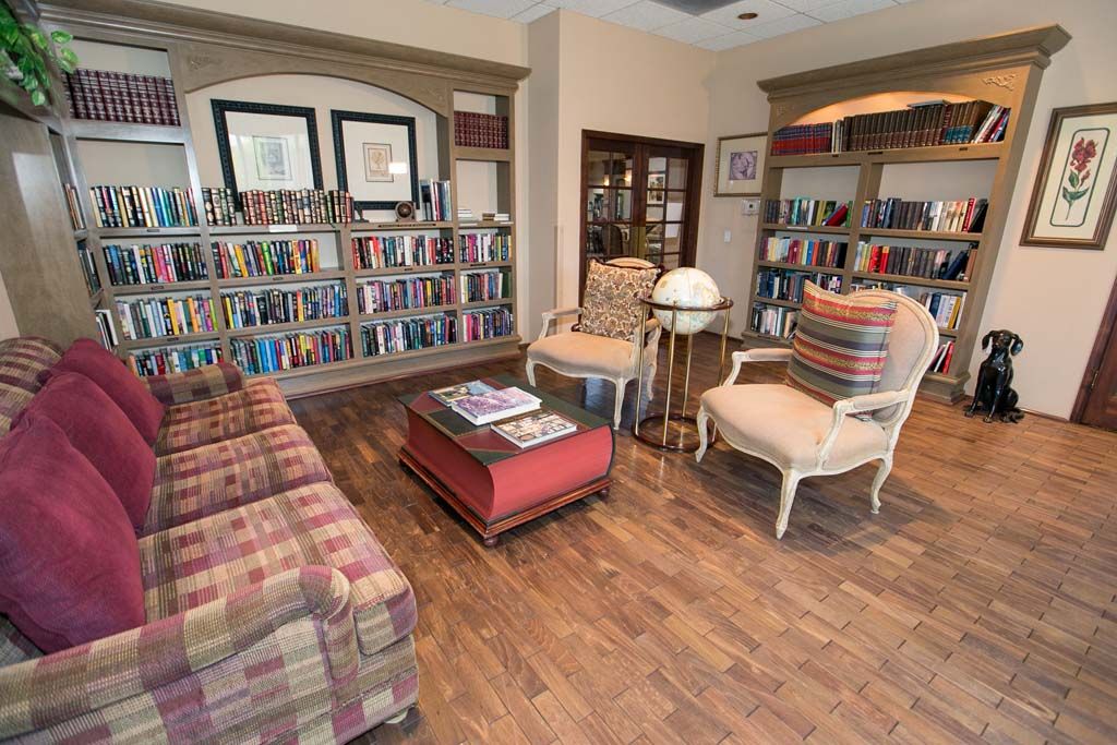 A cozy library space with bookshelves, comfortable armchairs, and a coffee table.