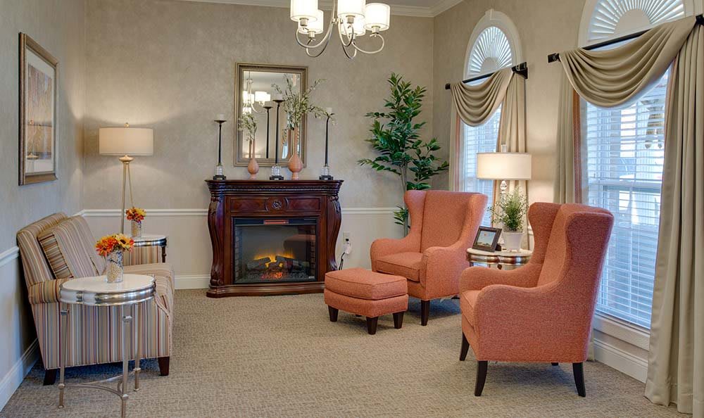 A cozy living room with a classic fireplace, elegant armchairs, and traditional decor.