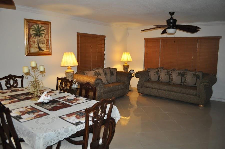 A cozy living room and dining area featuring sofas, a dining table, and ambient lighting from lamps.