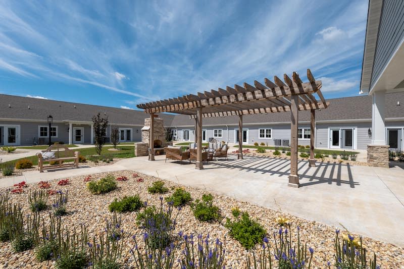 A serene outdoor area featuring a pergola and landscaped garden in front of a building.