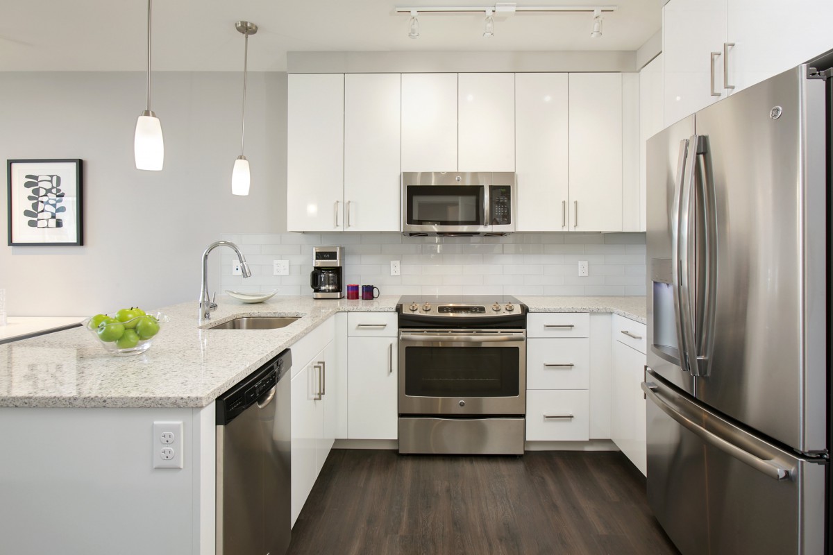 A modern kitchen with white cabinets and stainless steel appliances.