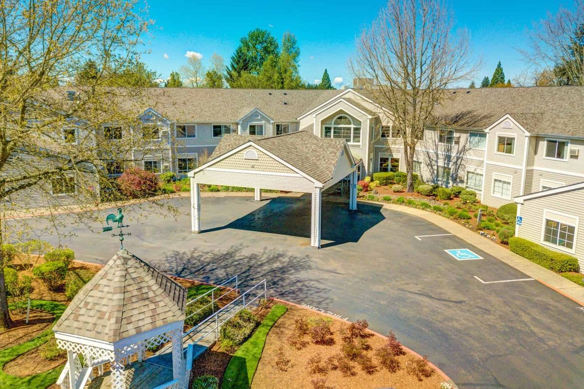 Aerial view of a residential building with landscaped gardens and a driveway.