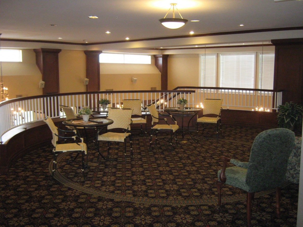 A cozy lounge area featuring various chairs and tables, illuminated by overhead lighting.