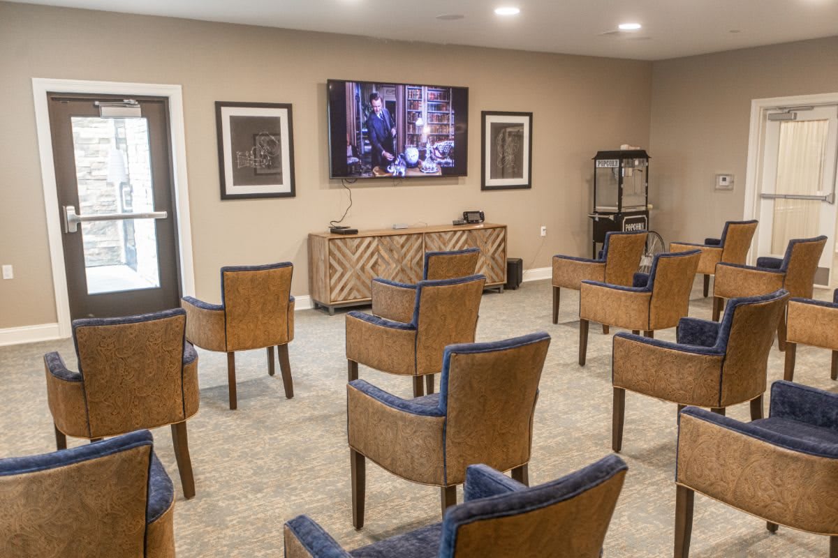 A cozy home theater setup with rows of comfortable chairs facing a large screen.