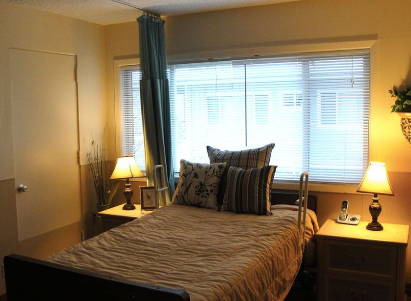 A cozy bedroom with a neatly made bed, decorative pillows, and soft lighting from bedside lamps near the window.