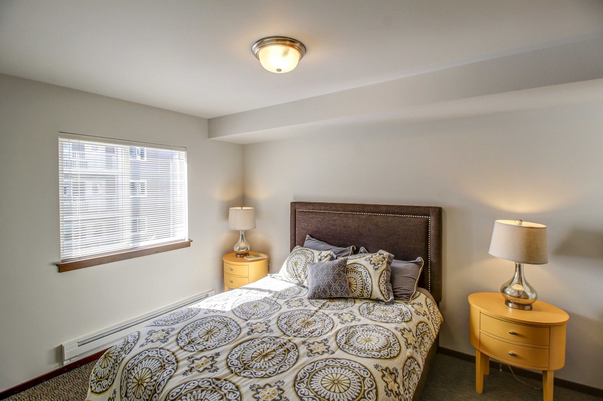 A cozy bedroom with a stylish bed and decorative pillows, flanked by two bedside tables and lamps.