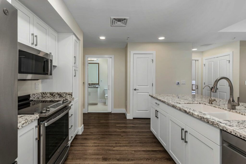 A modern kitchen with wood flooring and sleek countertops.