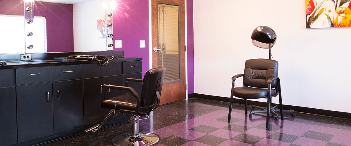 A modern salon interior with purple walls and checkered floor tiles.