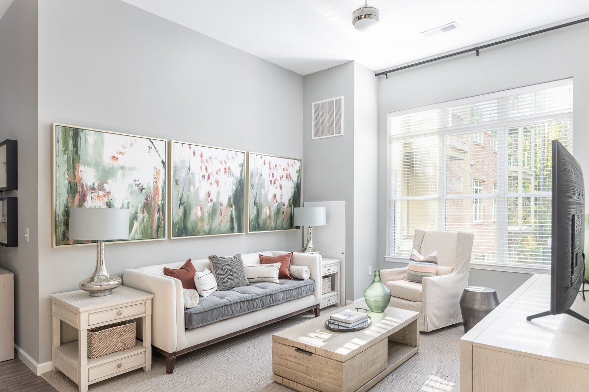 A modern living room with neutral tones, featuring elegant artwork and abundant natural light.