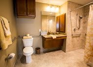 A well-lit modern bathroom with a toilet, sink, and shower area.