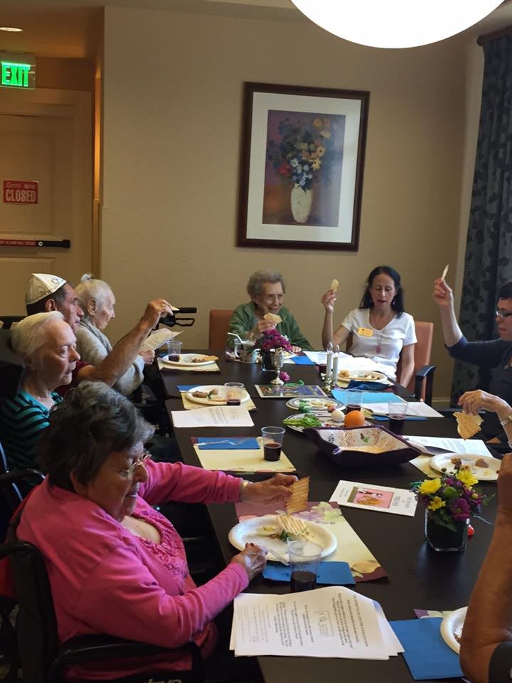 A group of seniors engaging in a painting activity around a table.