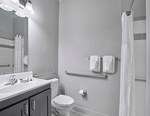 A clean and modern bathroom featuring a toilet, sink, mirror, and towel rack.