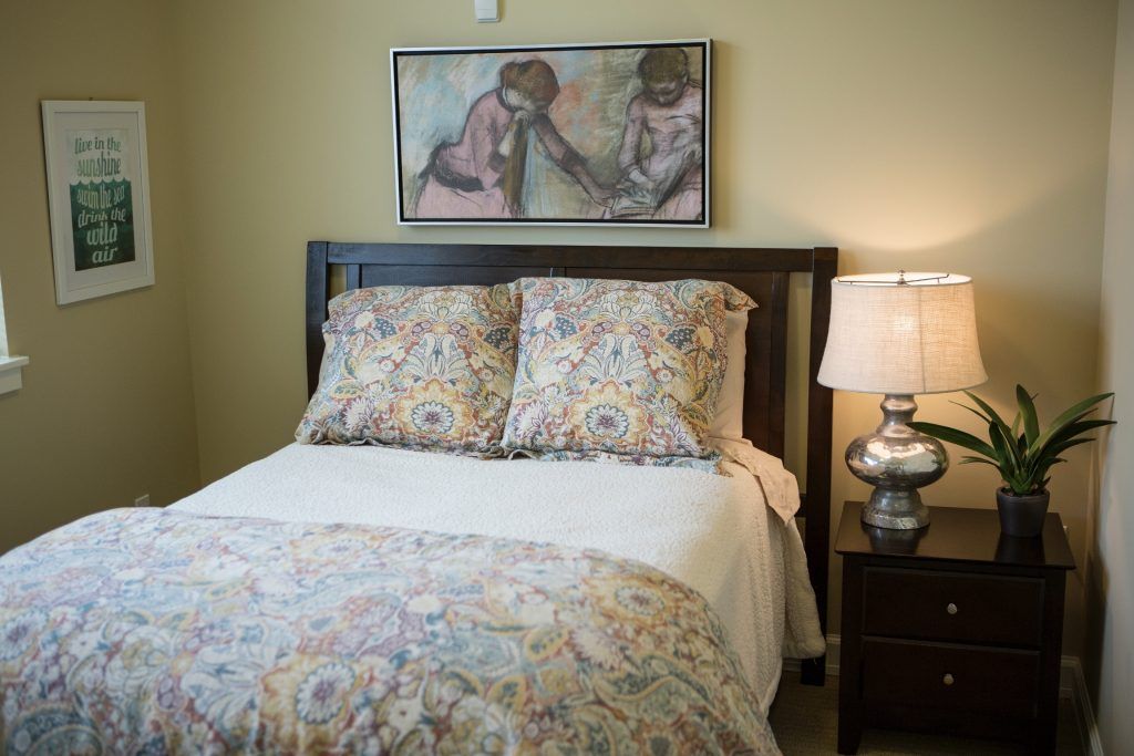 A cozy bedroom with patterned bedding and a stylish lamp beside the bed.