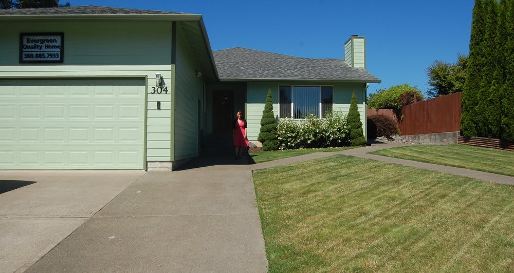 A suburban house with a green exterior and a neatly maintained lawn.