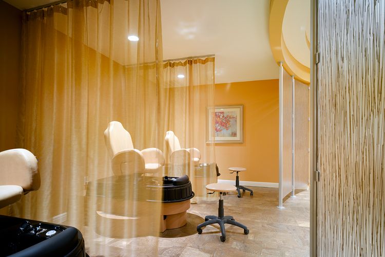 A cozy salon space with comfortable chairs and sheer curtains for privacy.