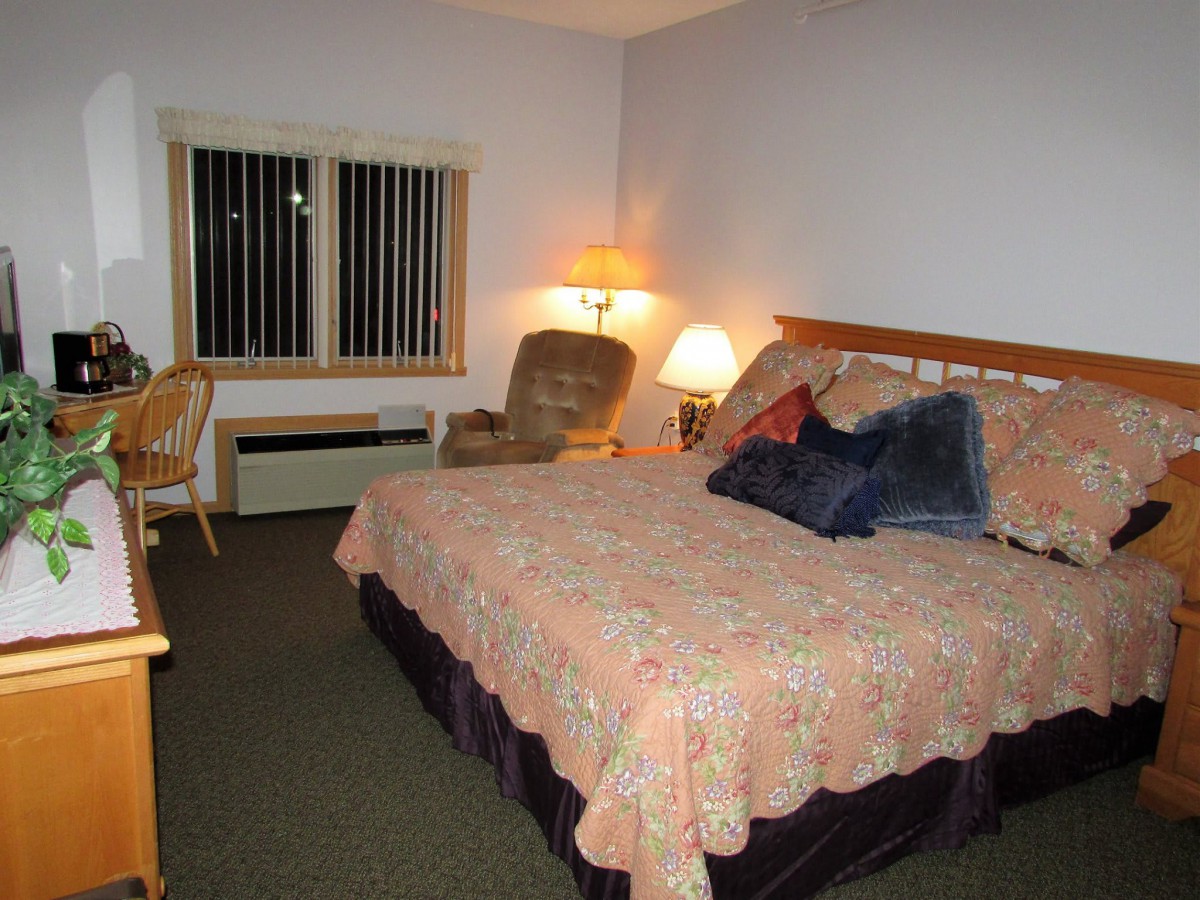 A cozy hotel bedroom with a large bed, soft lighting, and comfortable seating.