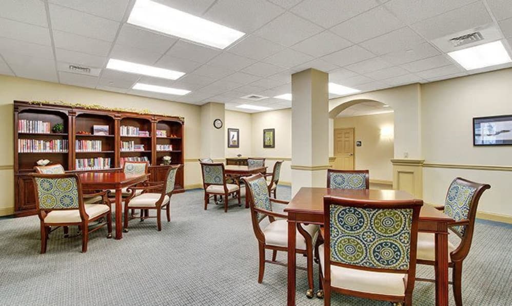 A well-lit library space with tables, chairs, and bookshelves.