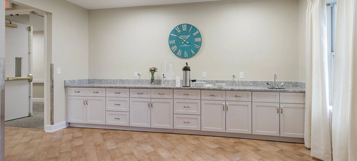 A modern kitchen with sleek cabinets and a large wall clock.