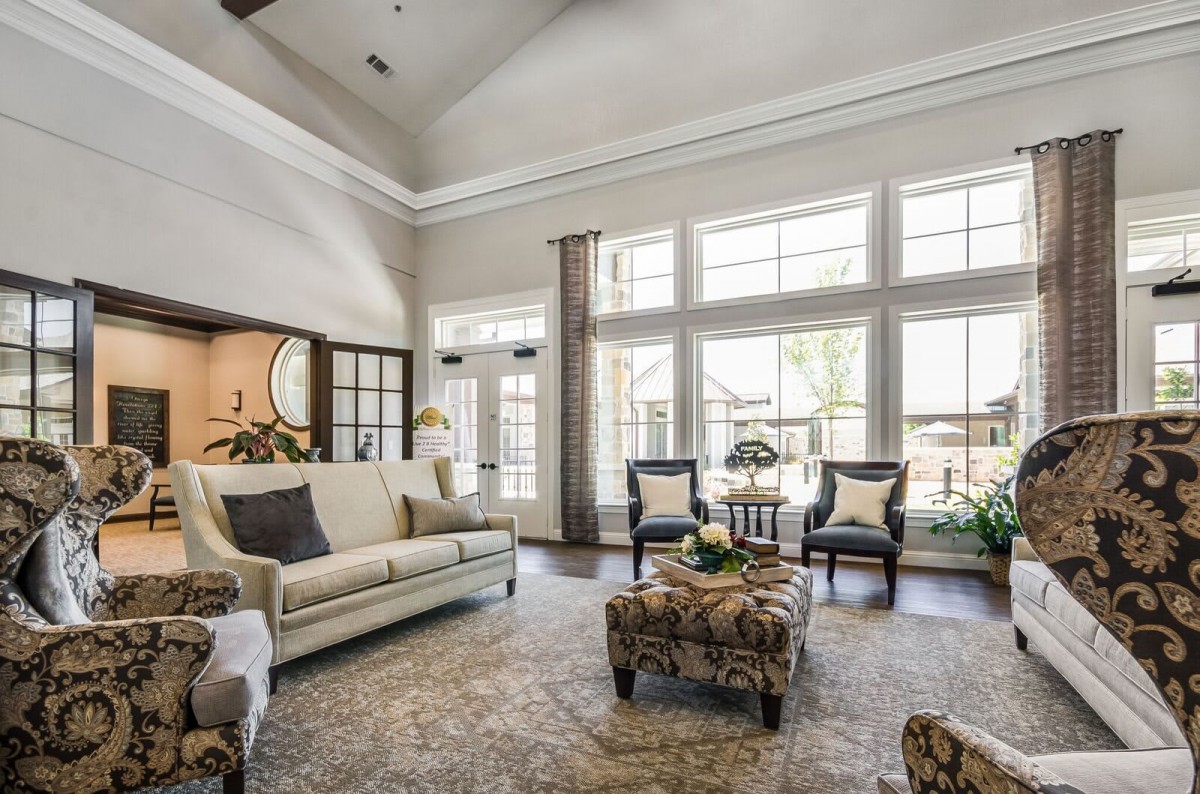 A spacious and elegant living room with ample natural light from large windows, featuring comfortable seating and tasteful decor.
