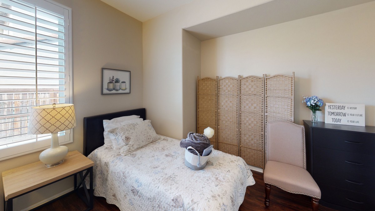 A cozy bedroom with a single bed, decorative screen, and minimalist decor.