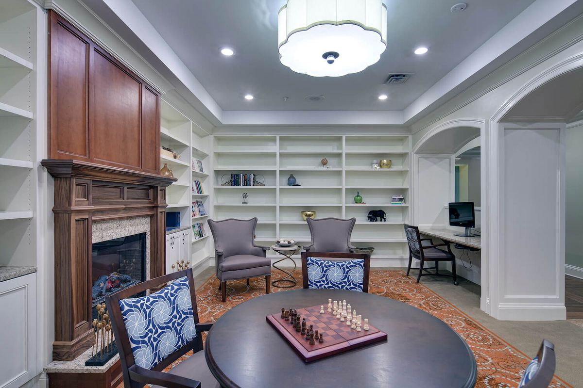 A cozy library with a chess board and comfortable seating.