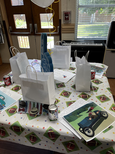 A festive setup featuring white gift bags and decorative elements on a printed tablecloth.